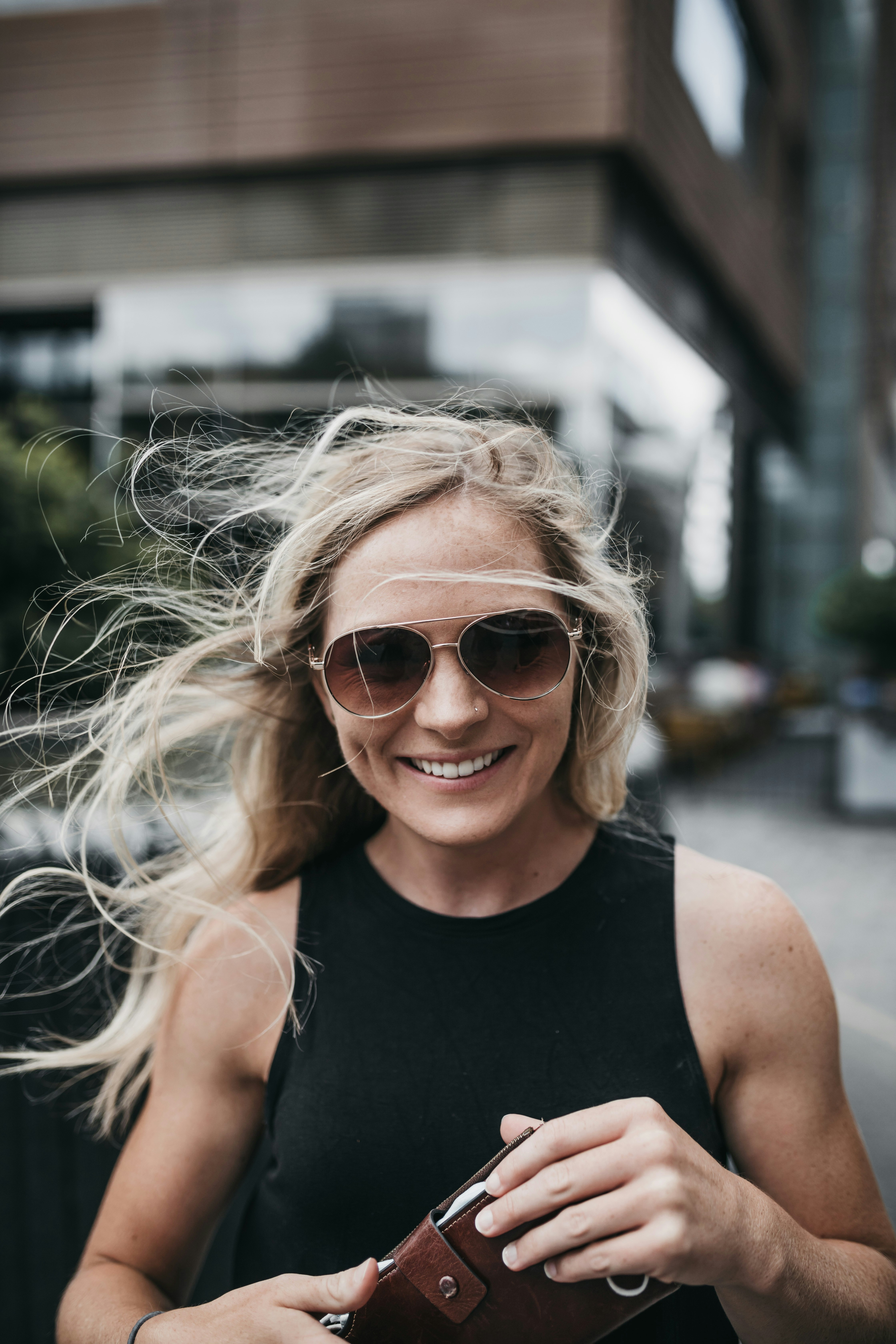 woman in black tank top wearing brown sunglasses smiling